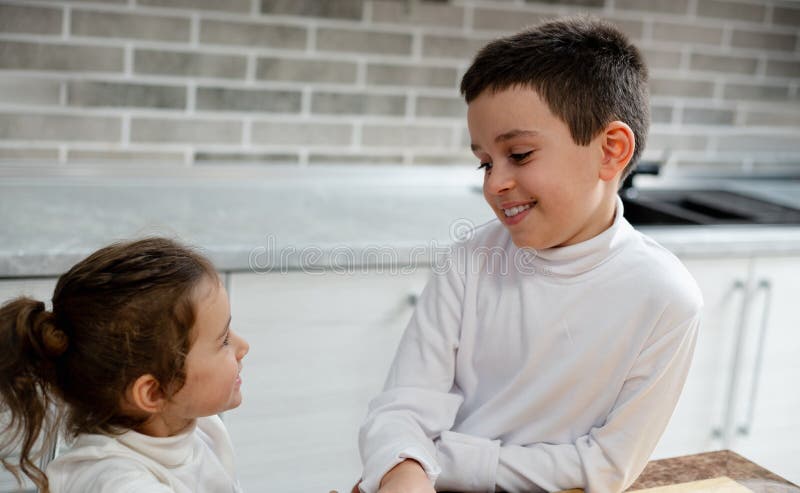 Un niño y una sonrisa de niña en sí. Los niños cocinan en su cocina foto de archivo libre de regalías