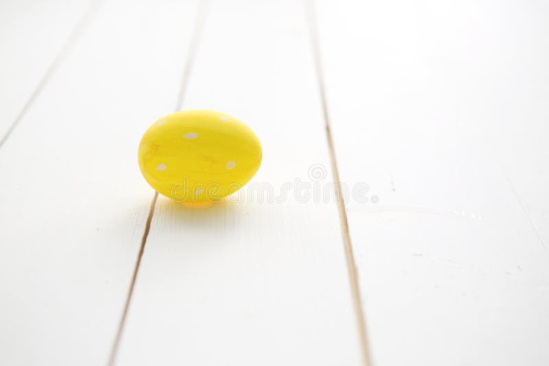 Un oeuf de pâques jaune sur le fond en bois blanc images stock Un oeuf de pâques jaune sur le fond en bois blanc images stock