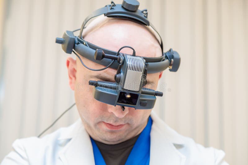 Un oftalmologo maschile controlla una visione del paziente con oftalmoscopio binoculare immagini stock