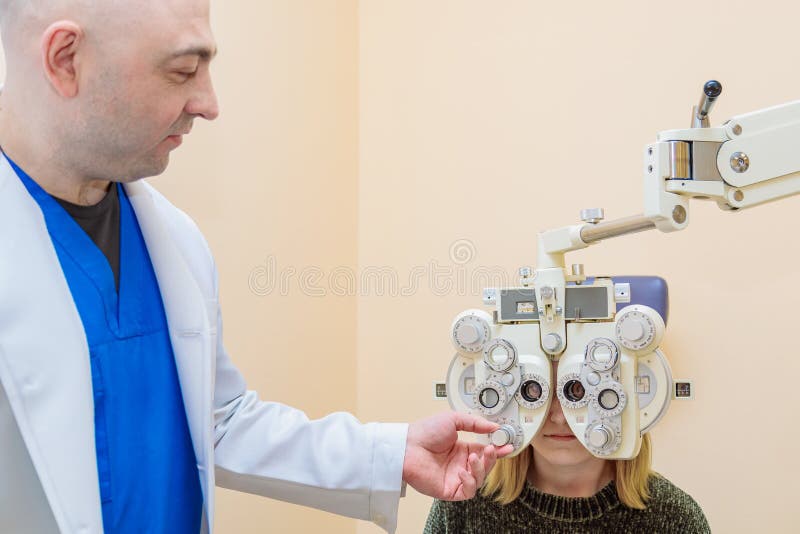 Un oftalmologo maschio controlla la vista di una ragazza usando un phoropher. trattamento visivo immagine stock libera da diritti