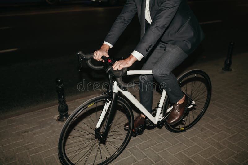 Un om nerecunoscut care merge pe bicicletă pe stradă pe timp de noapte stock photo