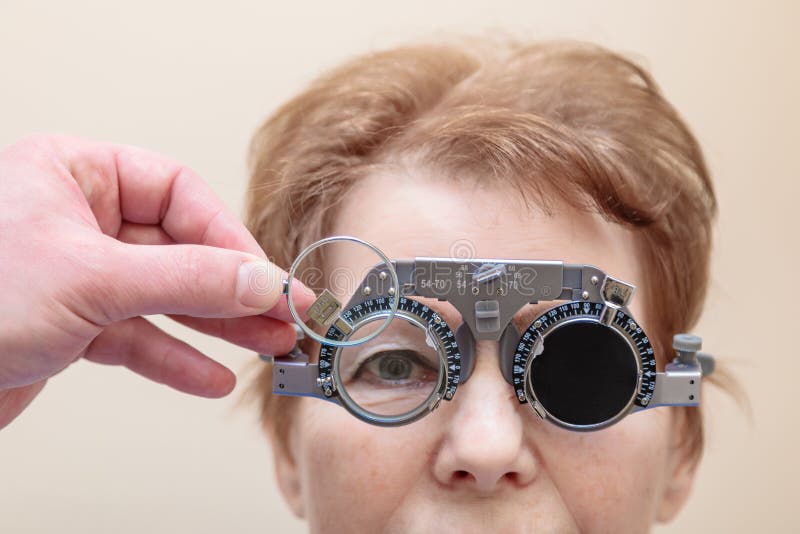 Un optometrista maschio controlla la vista di una donna adulta con una cornice di prova immagini stock