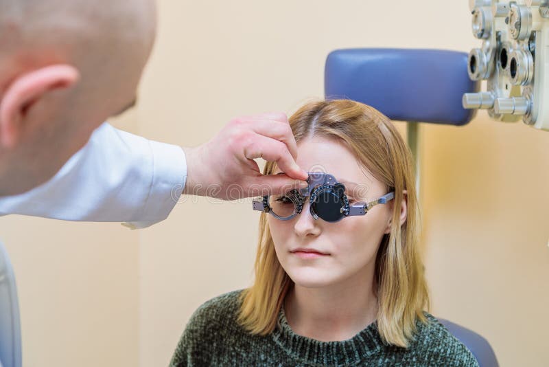Un optometrista maschio controlla la vista di una ragazza con una cornice di prova fotografie stock