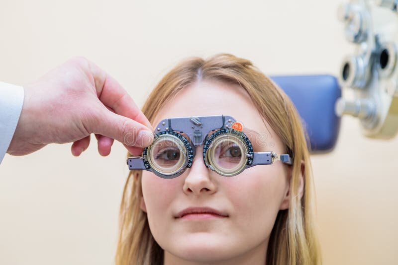 Un optometrista maschio controlla la vista di una ragazza con una cornice di prova immagini stock libere da diritti