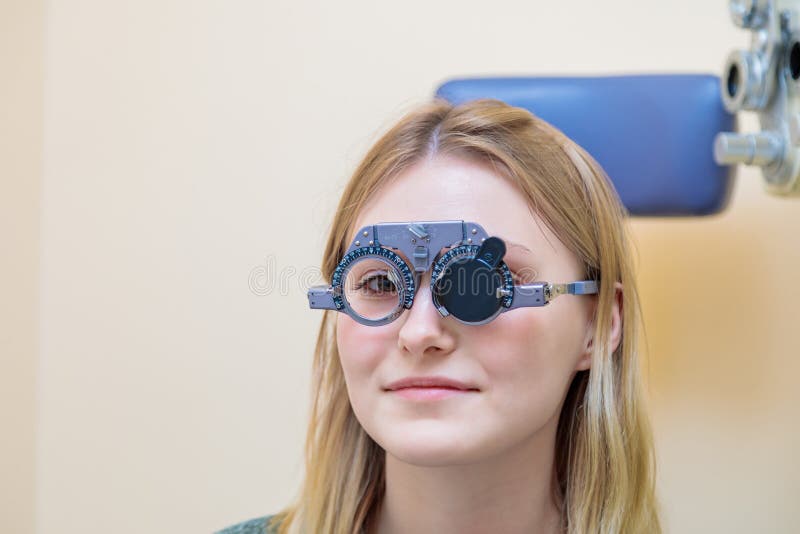 Un optometrista maschio controlla la vista di una ragazza con una cornice di prova immagini stock libere da diritti