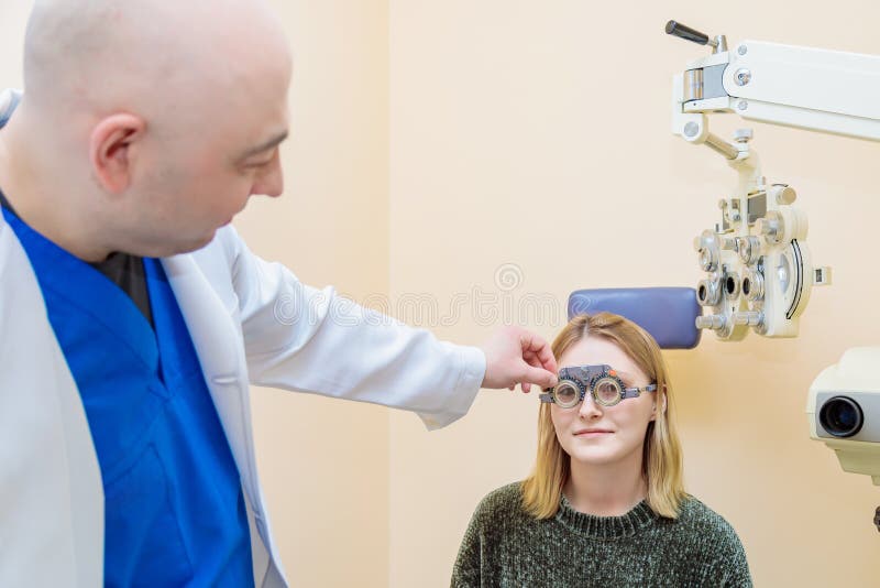 Un optometrista maschio controlla la vista di una ragazza con una cornice di prova fotografia stock libera da diritti