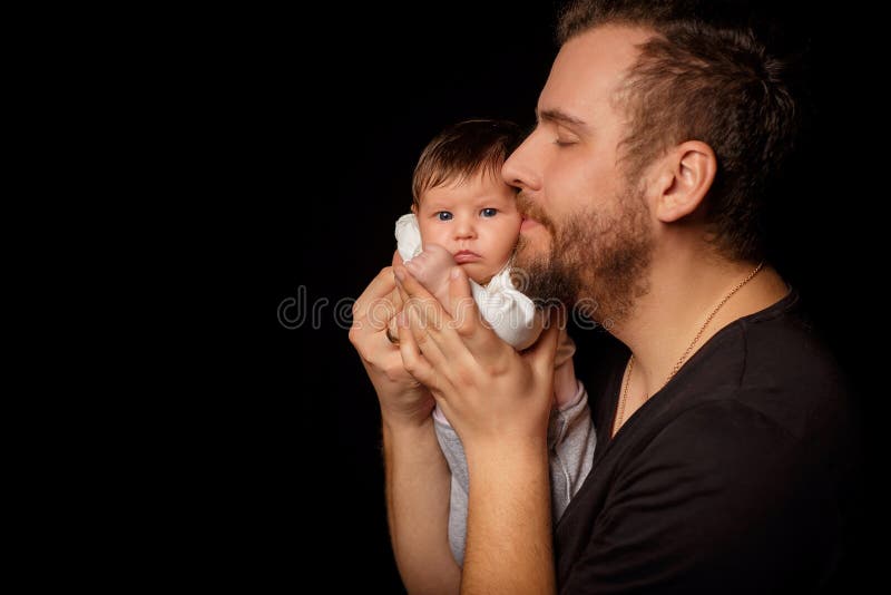 Un Pere Barbu Dans Un T Shirt Noir Est Titulaire D Un Nouveau Ne Le Pere Embrasse Et Enlace La Fille Ou Le Fils Sur Un Fond Noir Image Stock Image Du Paternite Fixation