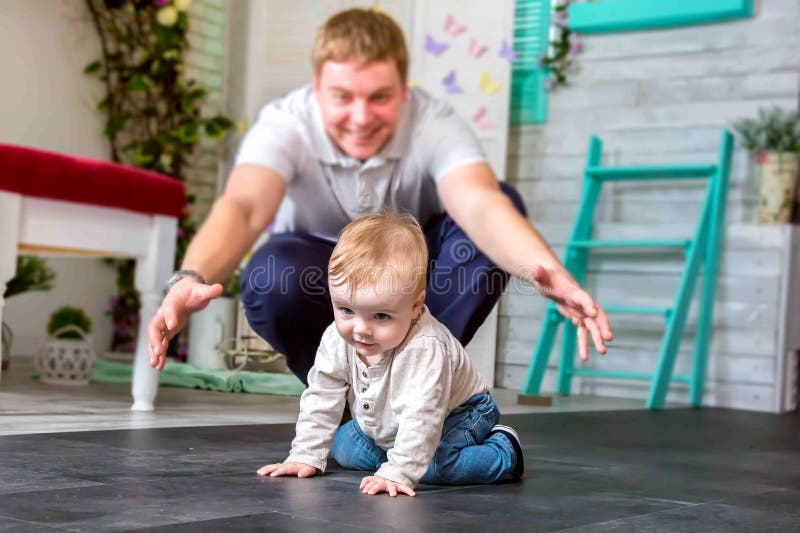 Un padre feliz que juega con el hijo Él está intentando coger a un niño feliz que se arrastra en todos los fours foto de archivo Un padre feliz que juega con el hijo Él está intentando coger a un niño feliz que se arrastra en todos los fours foto de archivo