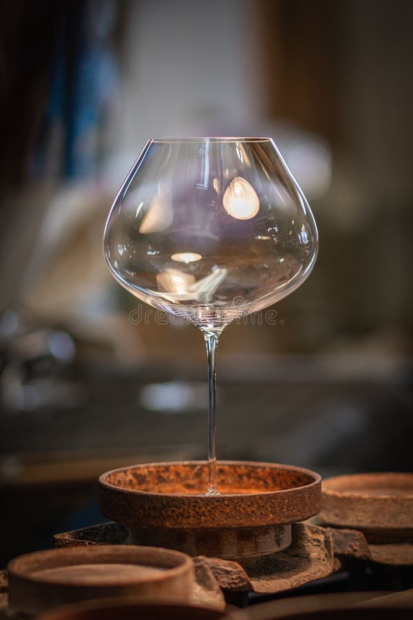 Un pahar mare de vin elegant, cu un castron larg și tulpină subțire înaltă se află pe o matriță circulară de culoare rugină stock photo
