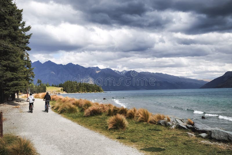 Un paio dei cavalieri della bicicletta gode del paesaggio magnifico di Queenstown, Nuova Zelanda immagini stock libere da diritti Un paio dei cavalieri della bicicletta gode del paesaggio magnifico di Queenstown, Nuova Zelanda immagini stock libere da diritti