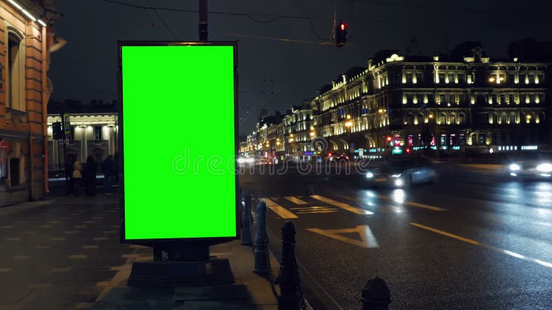 Un panneau d'affichage avec un écran vert sur une rue occupée de nuit clips vidéos
