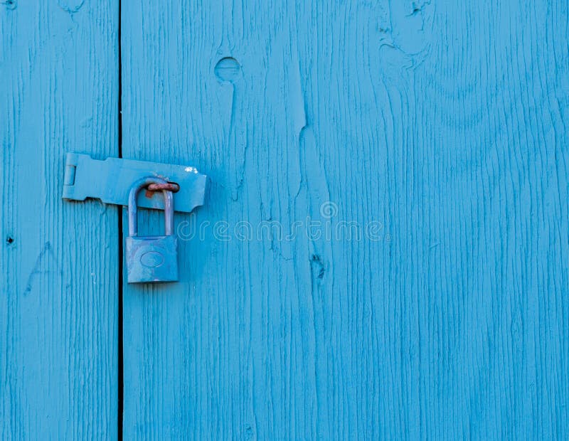 Un pannello di legno esterno bloccato. Un pannello di legno esterno chiuso con un lucchetto. la serratura e il blocco del pannello sono colorati in blu. una piccola quantità di uccello bianco che cade è sul latch. il grano di legno è visibile.