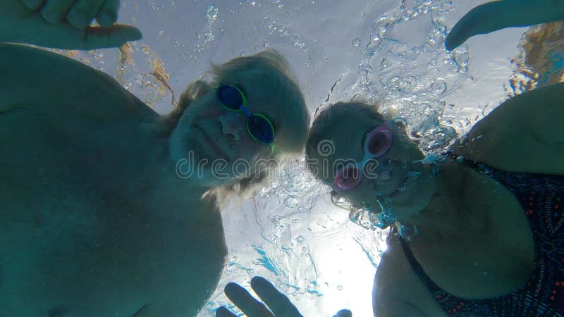 Un par de adultos mayores disfrutando del verano y divirtiéndose juntos en la piscina y sonriendo mirando a la cámara alegre feliz almacen de metraje de vídeo