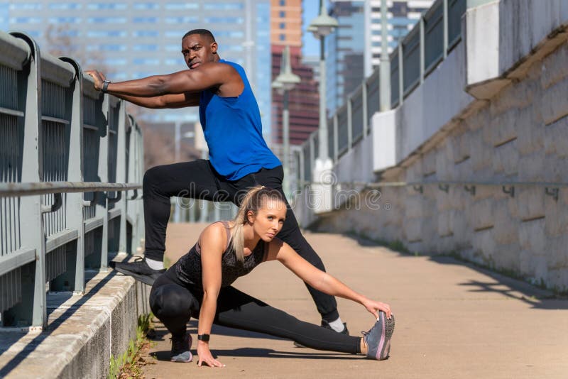 Un par de atletas serios y concentrados decididos preparándose para un largo ejercicio urbano de jog fitness moderna en el fondo d