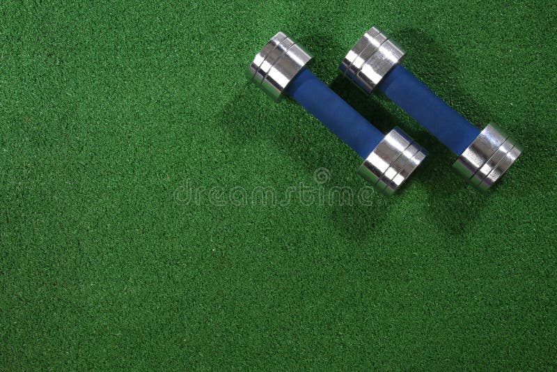 Un par de dumbells en un fondo de la hierba imágenes de archivo libres de regalías Un par de dumbells en un fondo de la hierba imágenes de archivo libres de regalías
