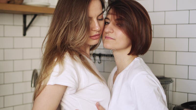 Un par de jóvenes lesbianas se abrazan suavemente en casa.