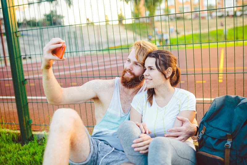 Un par europeo del ` s del hombre de pelo rojo y una barba y una mujer descansa después de jugar deportes al aire libre El indivi fotografía de archivo Un par europeo del ` s del hombre de pelo rojo y una barba y una mujer descansa después de jugar deportes al aire libre El indivi fotografía de archivo