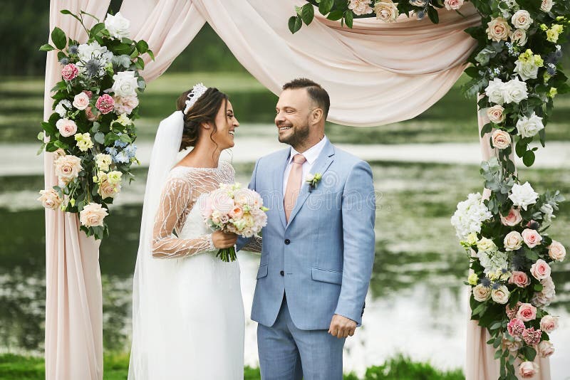 Un par hermoso de amantes cerca del arco que se casaba, adorn? con las flores frescas, mujer hermosa joven en la boda fotografía de archivo libre de regalías Un par hermoso de amantes cerca del arco que se casaba, adorn? con las flores frescas, mujer hermosa joven en la boda fotografía de archivo libre de regalías