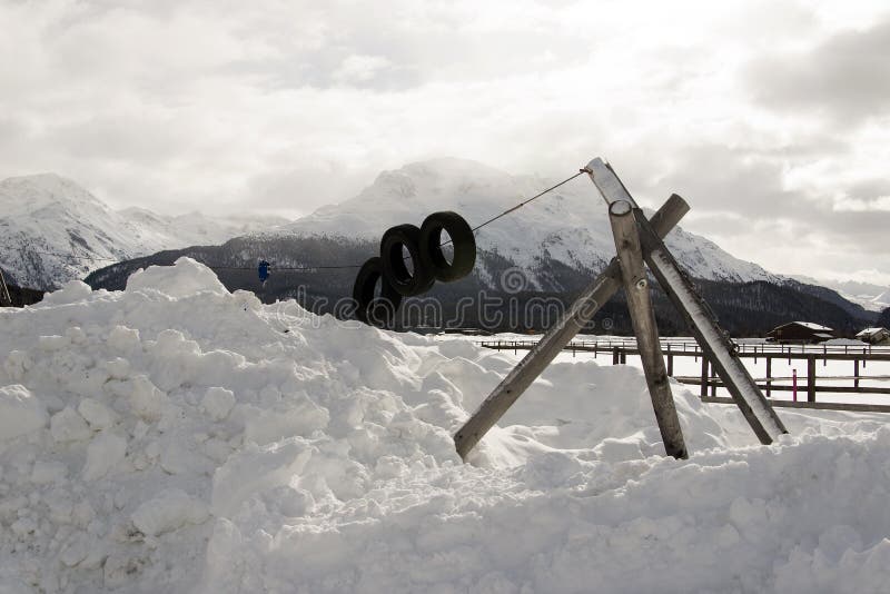 Un patio de los niños debajo de la nieve y de montañas nevosas y una pequeña ciudad en las montañas Suiza imagen de archivo libre de regalías Un patio de los niños debajo de la nieve y de montañas nevosas y una pequeña ciudad en las montañas Suiza imagen de archivo libre de regalías