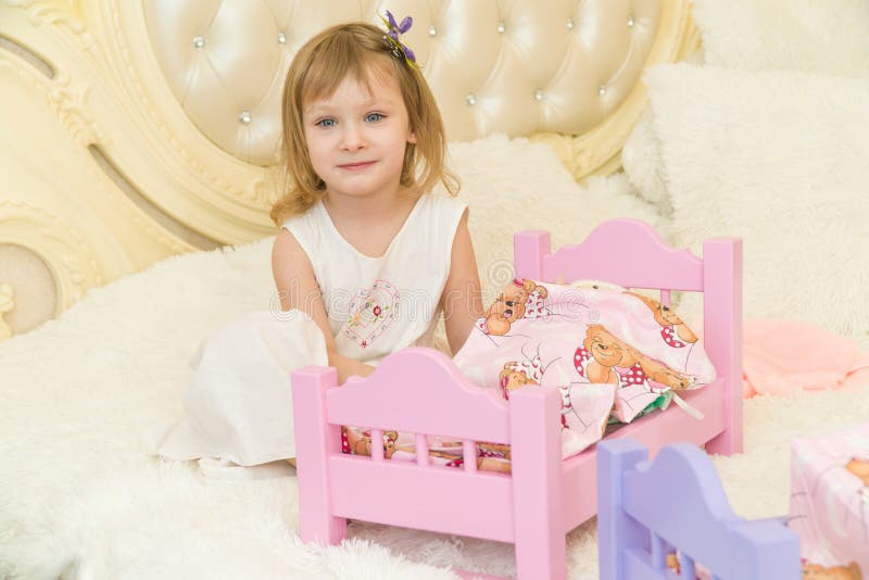 Un Pequeño Niño Preescolar Activo, Niña Bonita Con Un Pelo Rizado Rubio, Juegos Con Sus Muñecas, Las Pone Para Dormir Foto de archivo - Imagen de alegre, muchacha: 92774100