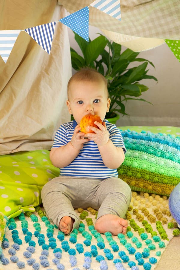 Un petit enfant est assis dans une tente pour enfants à la maison photos stock Un petit enfant est assis dans une tente pour enfants à la maison photos stock