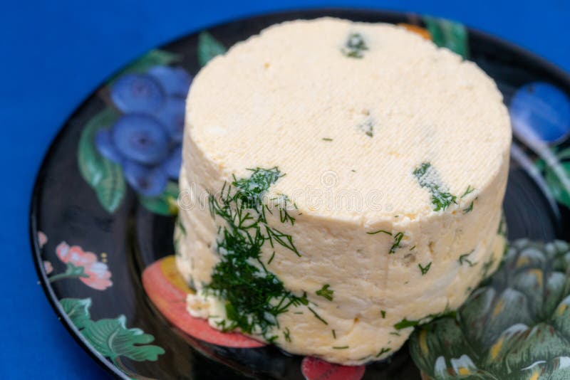 Un pezzo di formaggio fatto in casa con aneto e spezie su una piastra nera.