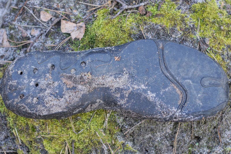 Un pezzo di suola di gomma nera proveniente da una scarpa sporca e lacerata immagine stock