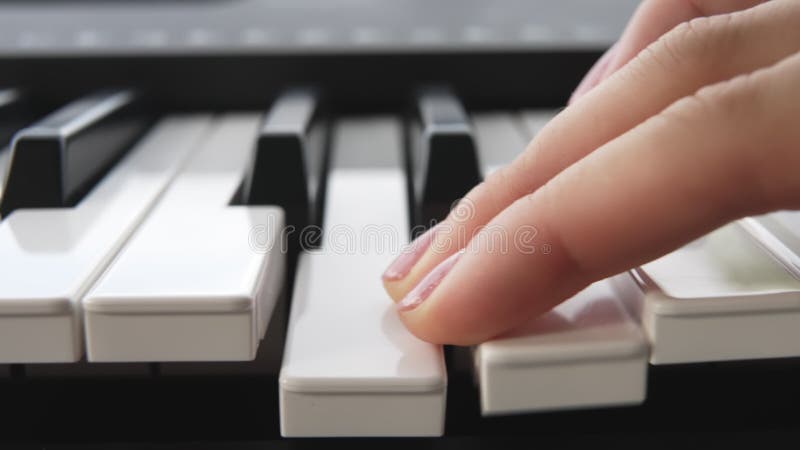 Un pianiste à la manucure rose passe son doigt sur les touches blanches du piano. la fille passe deux doigts sur les clés