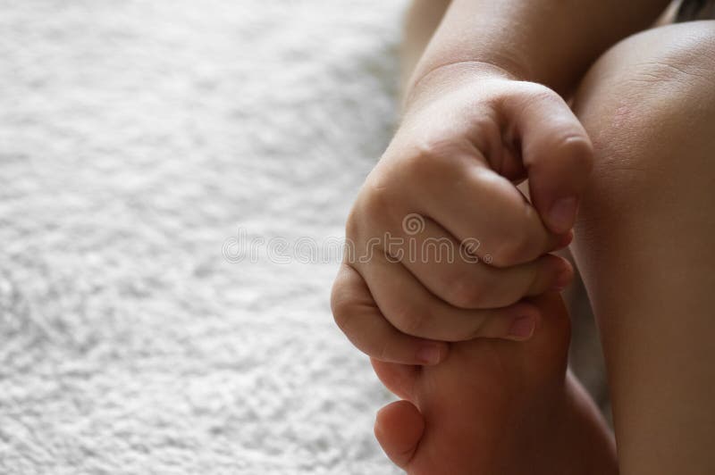 Un piccolo bambino tiene il suo braccio su un fondo bianco di lana pelle piedino Concetti per i bambini Concetto di assistenza di immagine stock Un piccolo bambino tiene il suo braccio su un fondo bianco di lana pelle piedino Concetti per i bambini Concetto di assistenza di immagine stock