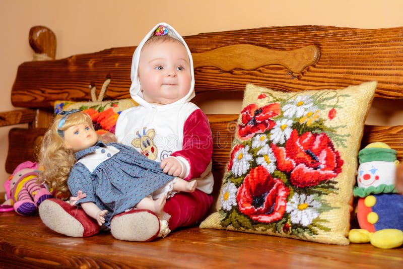 Un piccolo bambino in uno scialle che si siede su un sofà con i cuscini ricamati fotografia stock libera da diritti Un piccolo bambino in uno scialle che si siede su un sofà con i cuscini ricamati fotografia stock libera da diritti
