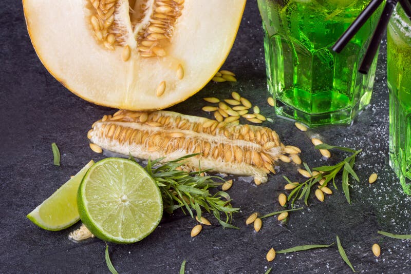 Un plan rapproché des fruits exotiques coupez le melon Cocktails verts d'alcool avec des pailles Feuilles d'estragon et chaux fra image libre de droits Un plan rapproché des fruits exotiques coupez le melon Cocktails verts d'alcool avec des pailles Feuilles d'estragon et chaux fra image libre de droits