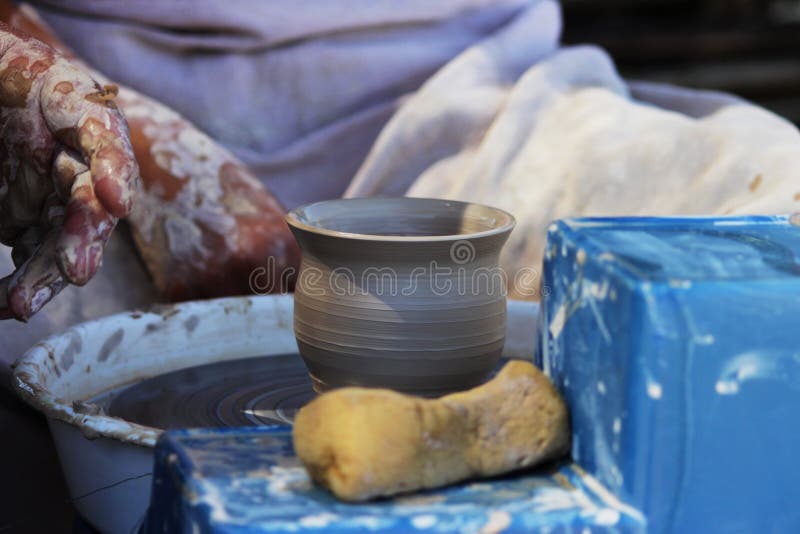 Un potier principal expérimenté enseigne une jeune fille à tourner un pot d'argile sur une roue du ` s de potier Tir de reportage images stock Un potier principal expérimenté enseigne une jeune fille à tourner un pot d'argile sur une roue du ` s de potier Tir de reportage images stock