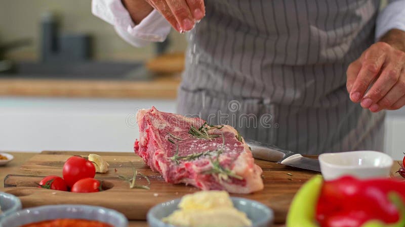 Un primer plano de un chef añadiendo especias en un trozo de carne almacen de video