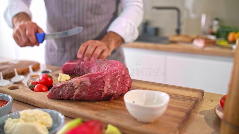 Un primer plano de las manos de los chefs cortando carne en un tablero de madera almacen de video