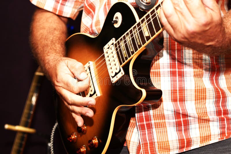 Un primo piano di un uomo che gioca una chitarra elettrica fotografia stock Un primo piano di un uomo che gioca una chitarra elettrica fotografia stock