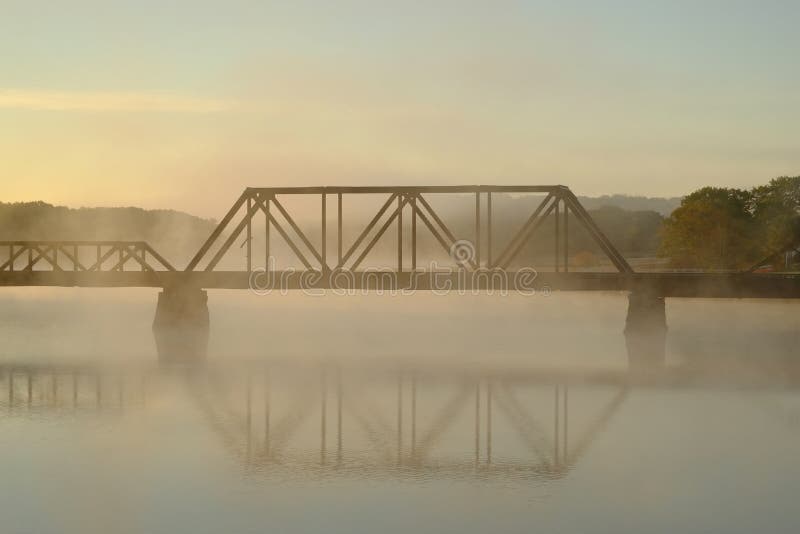 Un puente del ferrocarril sobre un río de niebla y brumoso MES temprano imagen de archivo libre de regalías Un puente del ferrocarril sobre un río de niebla y brumoso MES temprano imagen de archivo libre de regalías