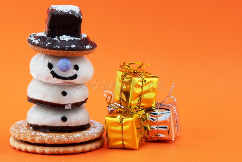 A candy snowman and a stack of present boxes isolated on orange backgrounf. A candy snowman and a stack of present boxes isolated on orange backgrounf