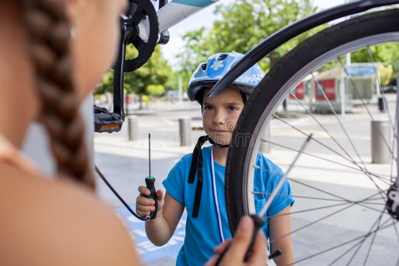 Un père aide son enfant à réparer une bicyclette mettant en vedette le travail d'équipe et l'apprentissage manuel photographie stock libre de droits