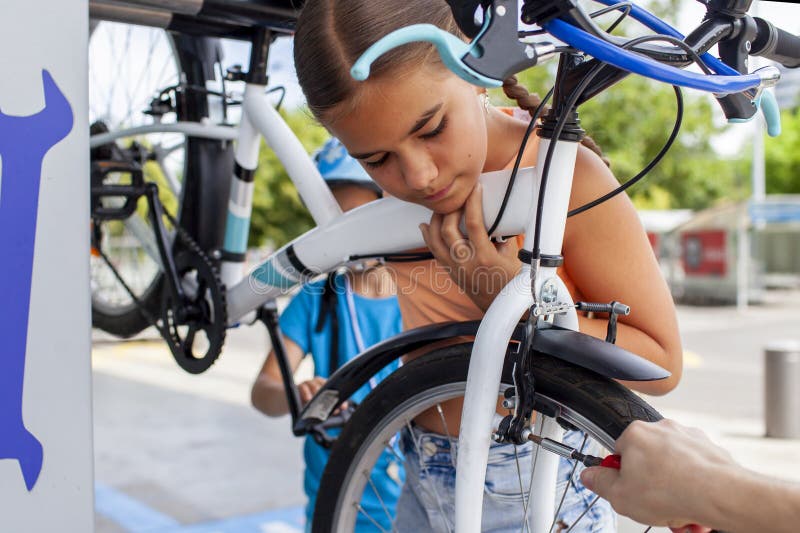 Un père aide son enfant à réparer une bicyclette mettant en vedette le travail d'équipe et l'apprentissage manuel images stock