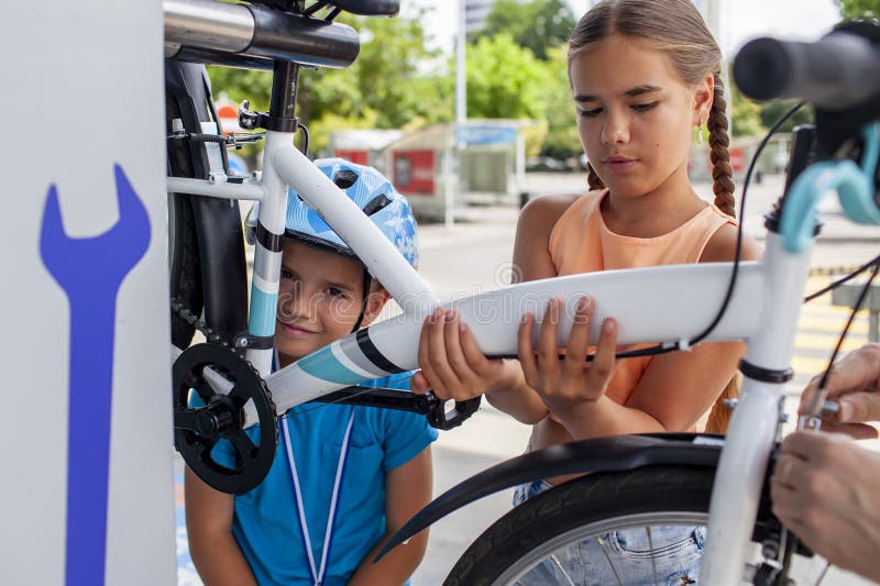 Un père aide son enfant à réparer une bicyclette mettant en vedette le travail d'équipe et l'apprentissage manuel photographie stock libre de droits
