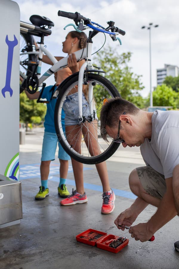 Un père aide son enfant à réparer une bicyclette mettant en vedette le travail d'équipe et l'apprentissage manuel images libres de droits