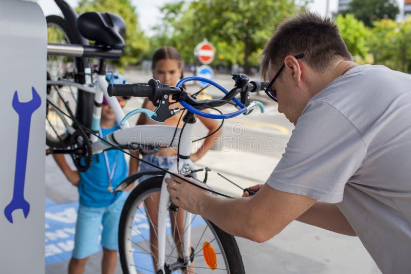 Un père aide son enfant à réparer une bicyclette mettant en vedette le travail d'équipe et l'apprentissage manuel photographie stock