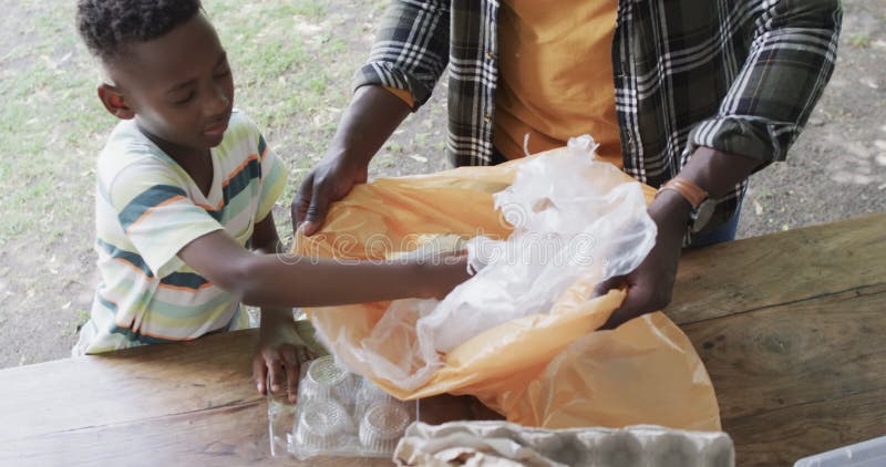 Un père et un fils afro-américains trient les matières recyclables dans un parc banque de vidéos