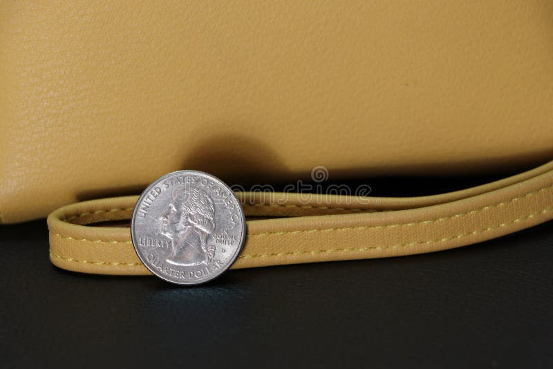Un quarto delle monete del dollaro americano su USD complementare con il portafoglio di colore della sabbia sul pavimento nero fotografia stock libera da diritti Un quarto delle monete del dollaro americano su USD complementare con il portafoglio di colore della sabbia sul pavimento nero fotografia stock libera da diritti
