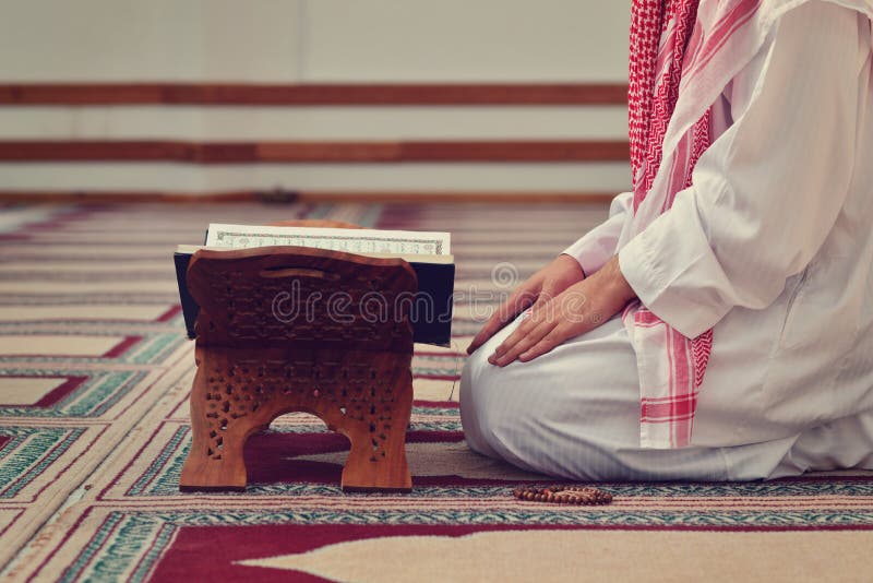 Un quran saint ouvert avec le support en bois avec les personnes de prière à l'arrière-plan photo libre de droits