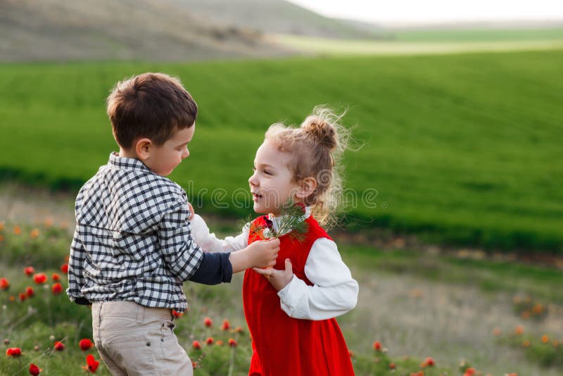 Un ragazzino che dà i fiori ad una ragazza Il concetto di amore fotografie stock Un ragazzino che dà i fiori ad una ragazza Il concetto di amore fotografie stock