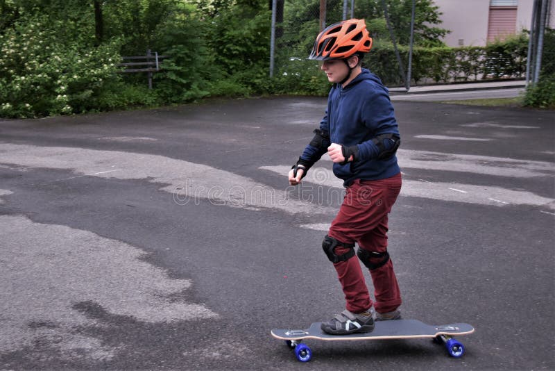 Un ragazzino che fa skateboarding su un terreno sportivo con l'asfalto fotografia stock Un ragazzino che fa skateboarding su un terreno sportivo con l'asfalto fotografia stock