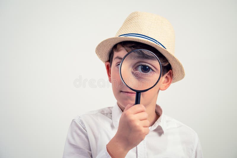 Un ragazzino che guarda una macchina fotografica con ingrandimento e ricerca fotografia stock libera da diritti Un ragazzino che guarda una macchina fotografica con ingrandimento e ricerca fotografia stock libera da diritti
