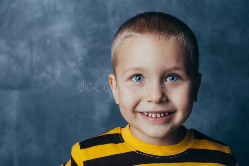 Un ragazzino posa davanti ad un muro di cemento grigio-blu E fotografia stock libera da diritti Un ragazzino posa davanti ad un muro di cemento grigio-blu E fotografia stock libera da diritti
