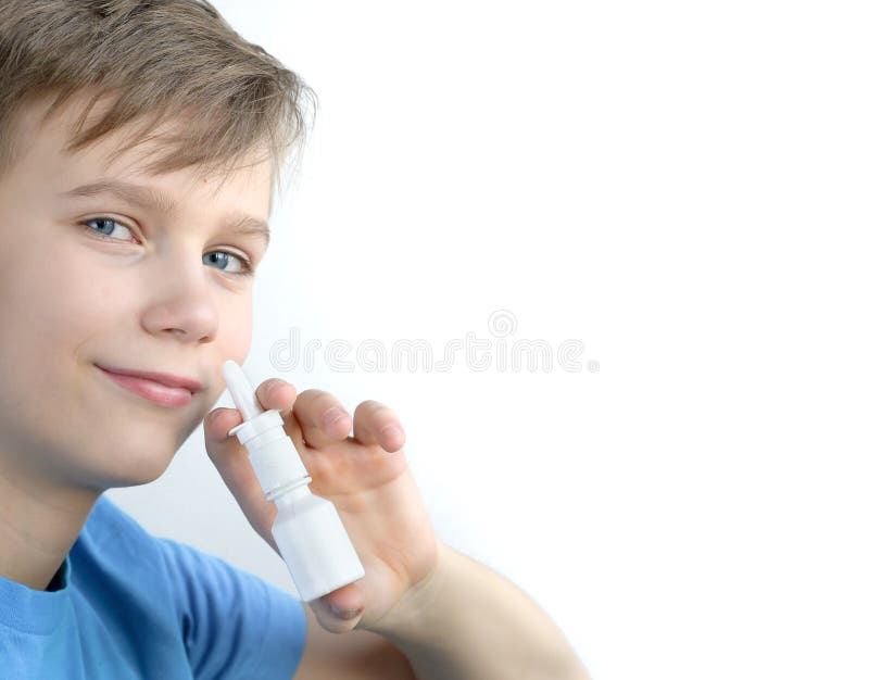 A boy of twelve years old sprays nasal spray on a white background. Teenager in blue shirt using nasal spray in good mood. A boy of twelve years old sprays nasal spray on a white background. Teenager in blue shirt using nasal spray in good mood